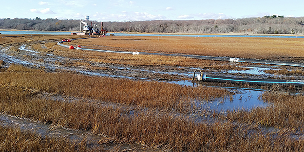 Lengths of pipe pumping the material from the river onto the sinking areas of the marsh
