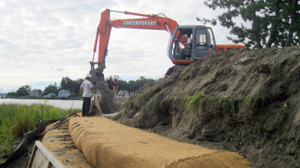 Workers fill the open envelopes with sand and then hand stitch them closed