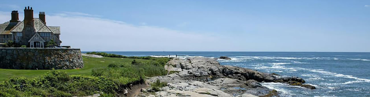 Photo showing the cliff walk with rocky shoreline, the ocean, and the Cliff Walk Manor